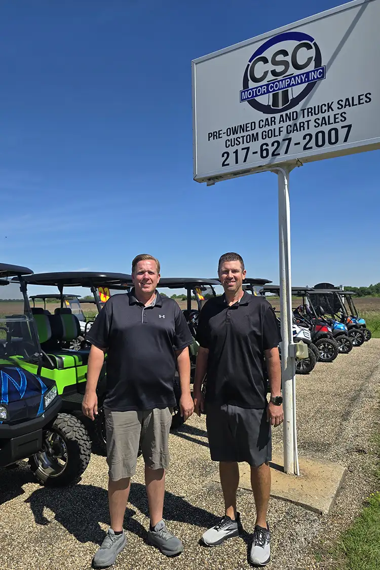 CSC Motor Company staff members standing company sign outside the dealership near Springfield, IL