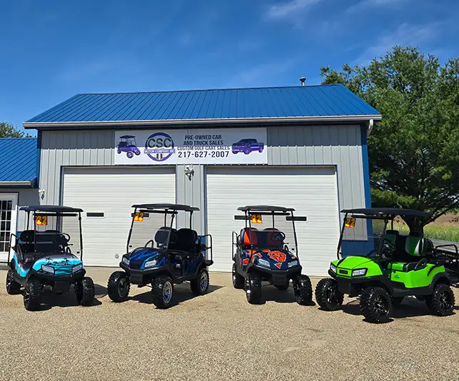 Four custom built golf carts lined up outside CSC Motor Company dealership building near Springfield, IL