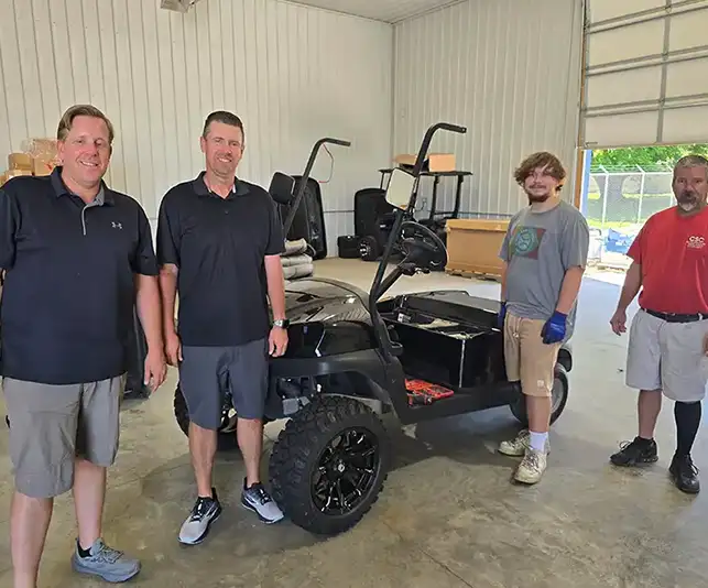 CSC Motor Company staff posing with a partially built black golf cart in the Springfield, IL shop