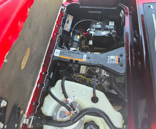 Battery and wiring compartment of red golf cart with fuel tank visible for repair services – CSC Motor Company Springfield, IL