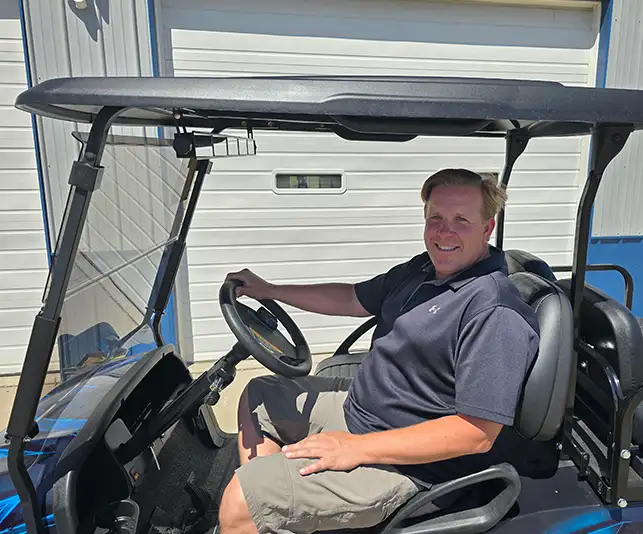CSC Motor Company owner sitting in a blue golf cart outside the Springfield, IL dealership