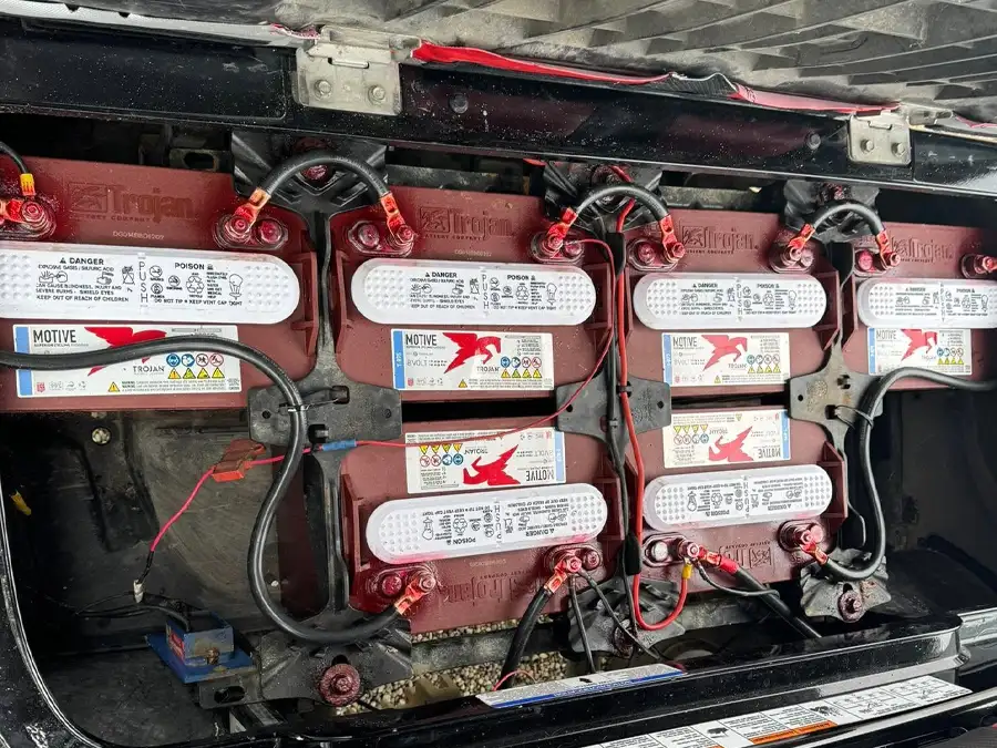 Trojan batteries wired in golf cart battery bay with visible terminals – CSC Motor Company Springfield, IL